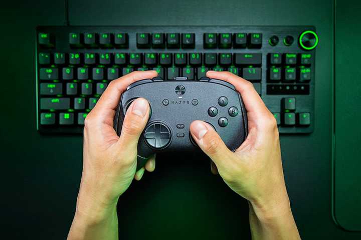 Razer Wolverine V3 Pro 8K PC being held over a keyboard