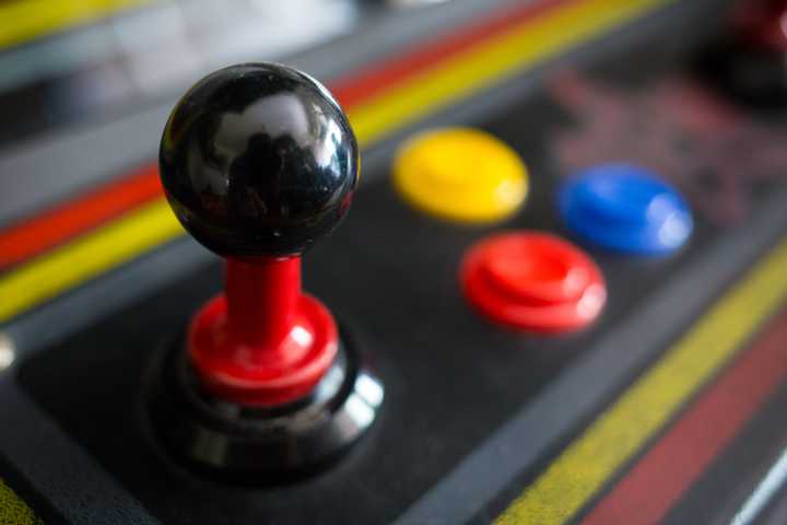 A close up view of a standup arcade machine's joystick and its three buttons. 