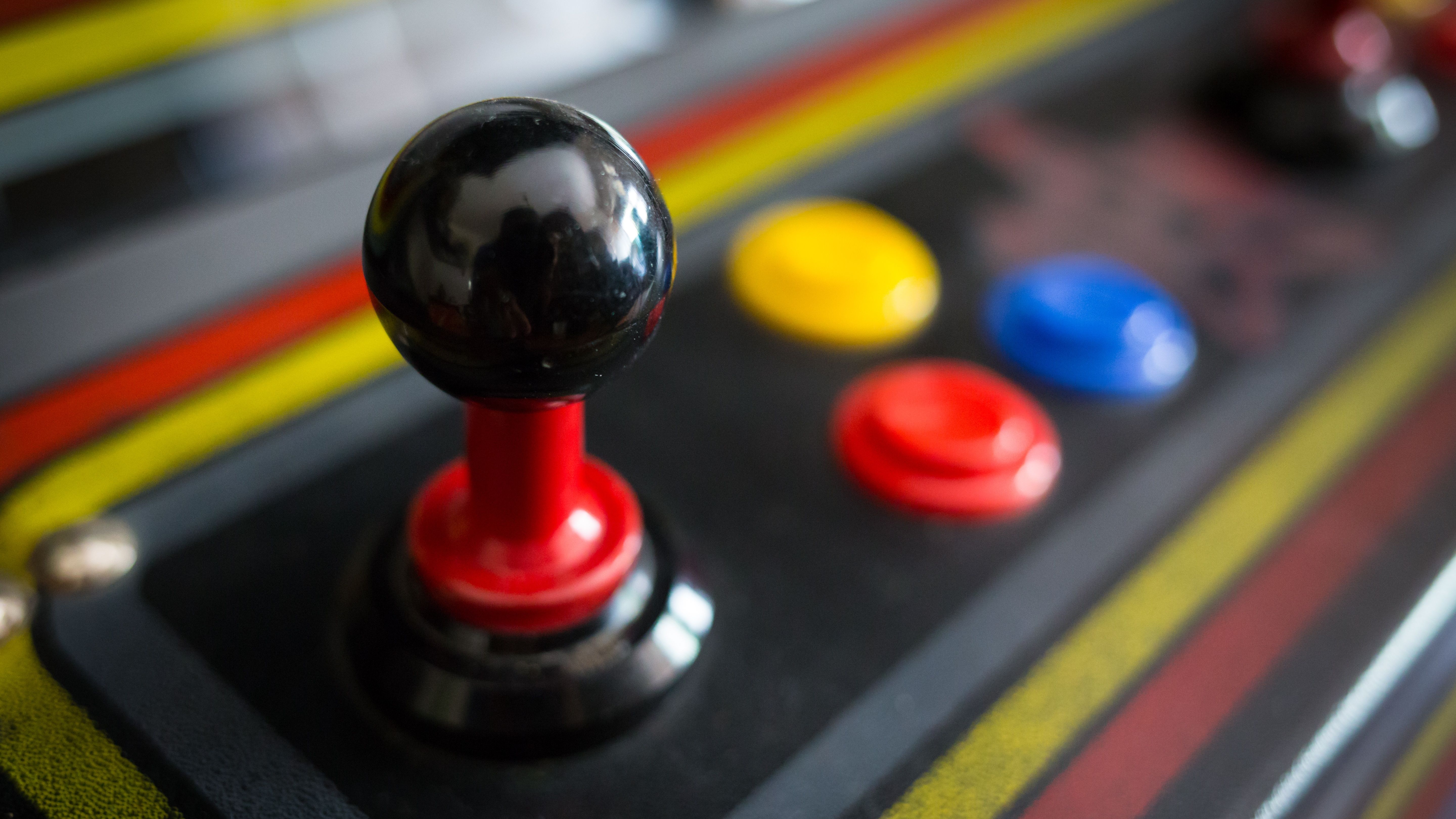 A close up view of a standup arcade machine's joystick and its three buttons. 