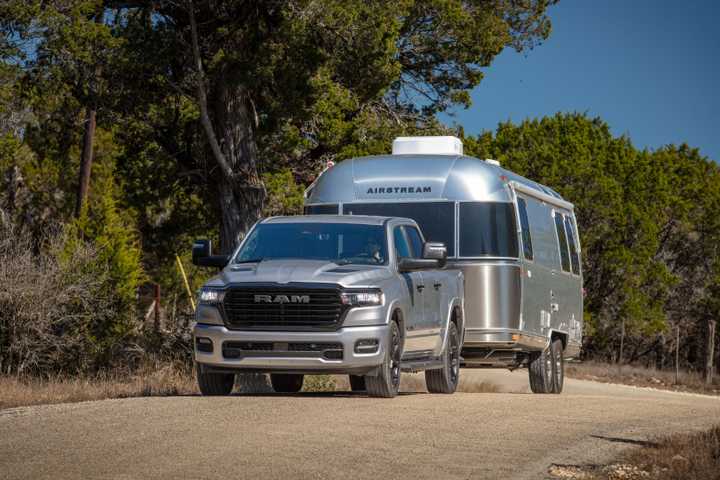 Front 3/4 shot of a 2025 Ram 1500 with a trailer hitched to the back