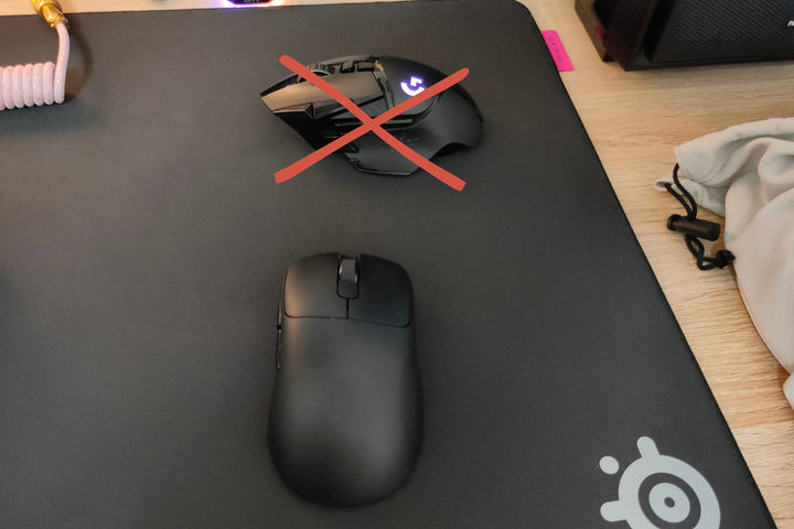 The Ajazz AJ179 Pro lightweight mouse with the Logitech G502 Lightspeed crossed out on a black SteelSeries mouse pad.