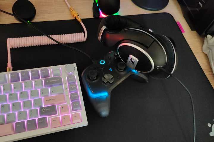 A wired keyboard, controller, and headphones on a black mousepad.