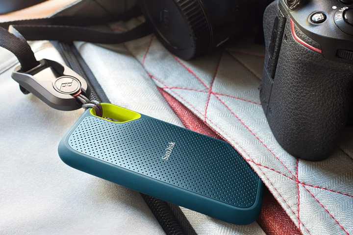 SanDisk 4TB Extreme Portable SSD tied to a bag next to camera equipment.