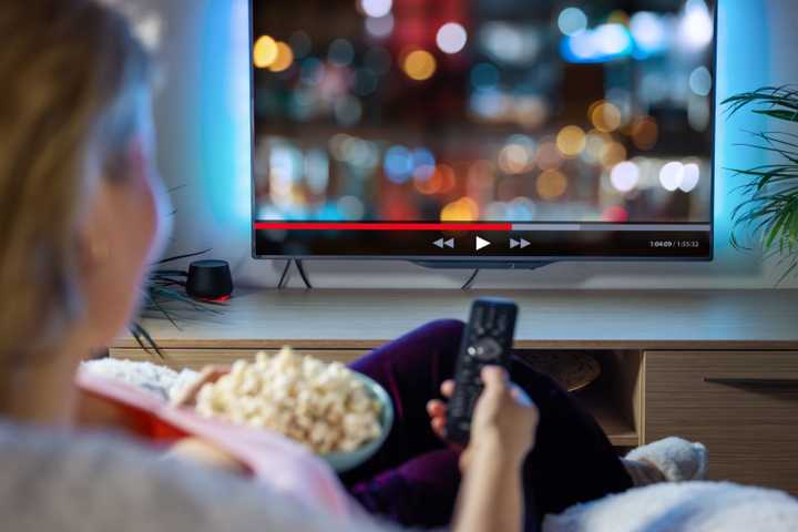 Woman relaxing at home in evening and watching TV.