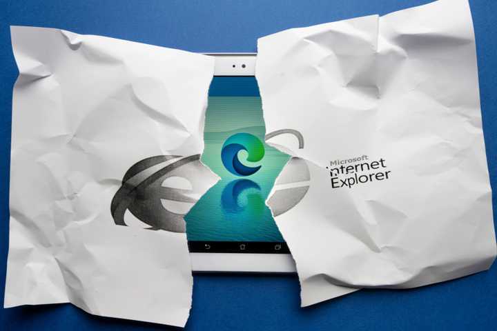 The symbol of Internet explorer on a sheet of torn paper with the symbol of the new browser Microsoft Edge on a tablet screen in the background