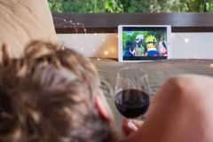 A person drinking wine in bed while watching Naruto.