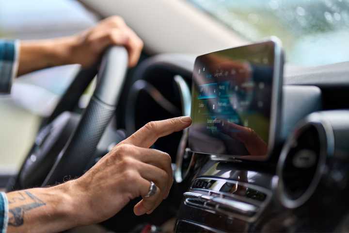 Hand reaching out to operate a touch screen.