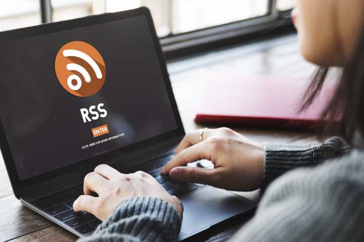 A woman sits in front of a laptop showing the RSS logo.
