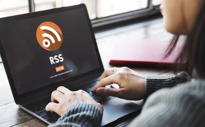A woman sits in front of a laptop showing the RSS logo.