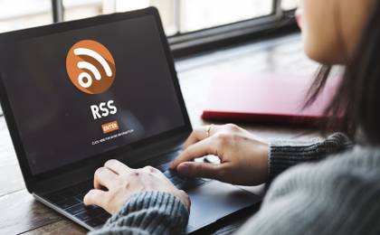 A woman sits in front of a laptop showing the RSS logo.