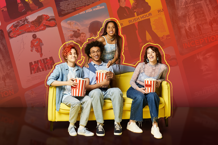 Some friends on a couch holding a bucket of popcorn, with various movie covers in the background.
