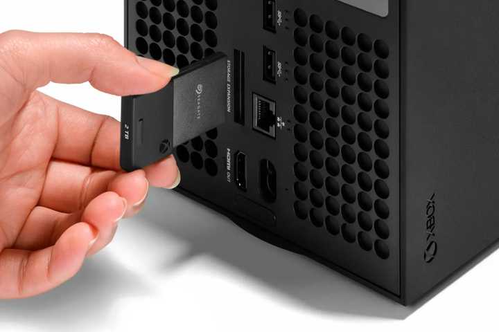 Someone putting the Seagate Storage Expansion Card 2TB Solid State Drive into an xbox