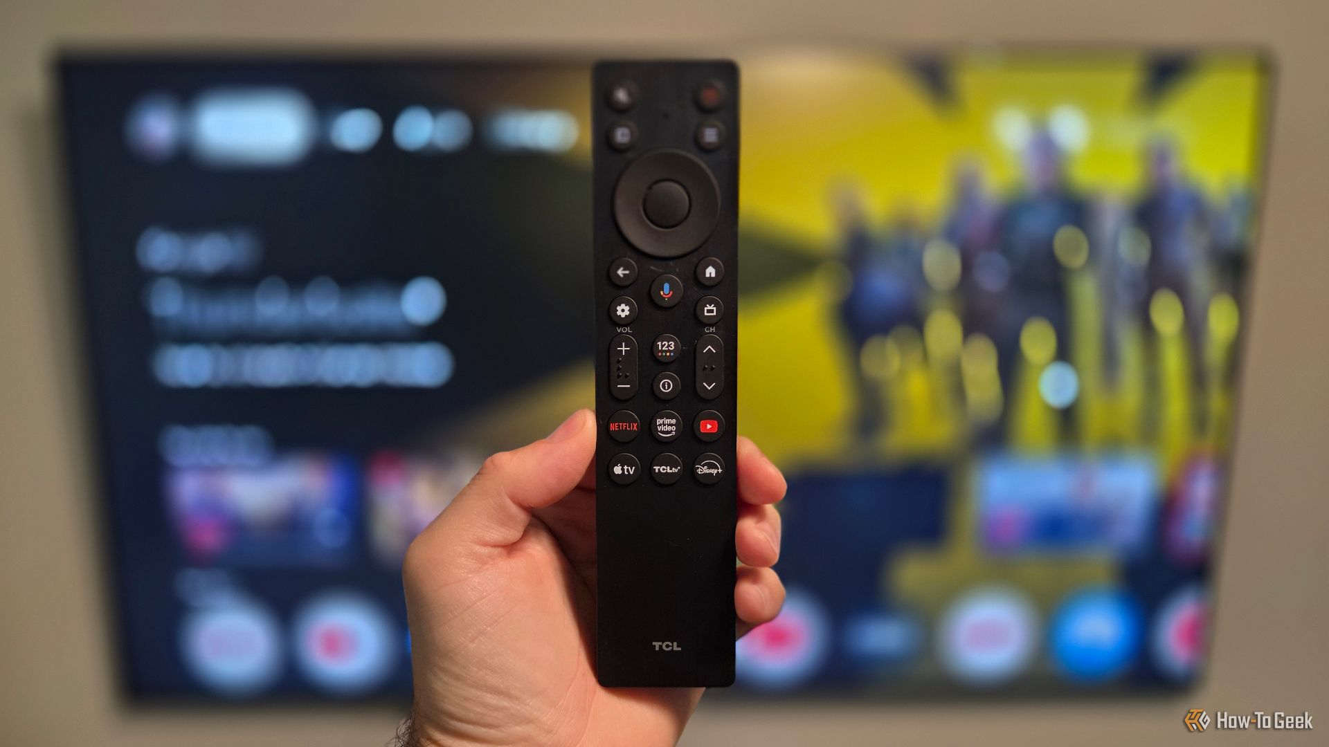 Hand holding a TCL QM6K TV remote. 