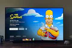 The Simpsons on Disney+ on a 4K TV in a green living room.