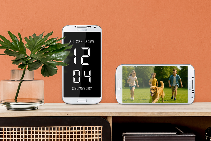 Two phones on a table, one displaying a digital clock, the other a photo.