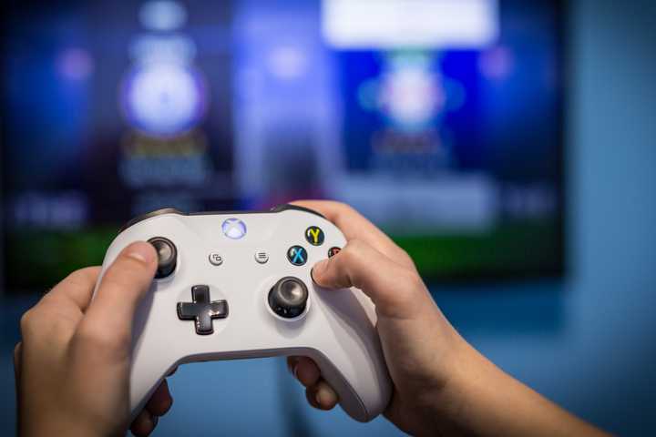 A photo of two hands using an Xbox controller to control the media PC in the foreground.