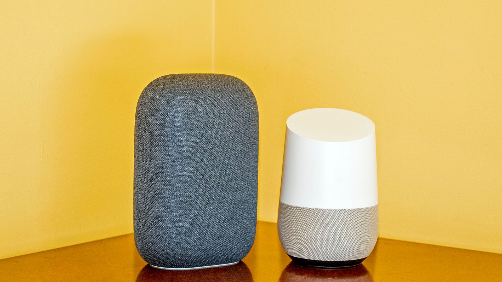 A Nest Audio next to a Google Home, showing it is skinner and taller than the Home.
