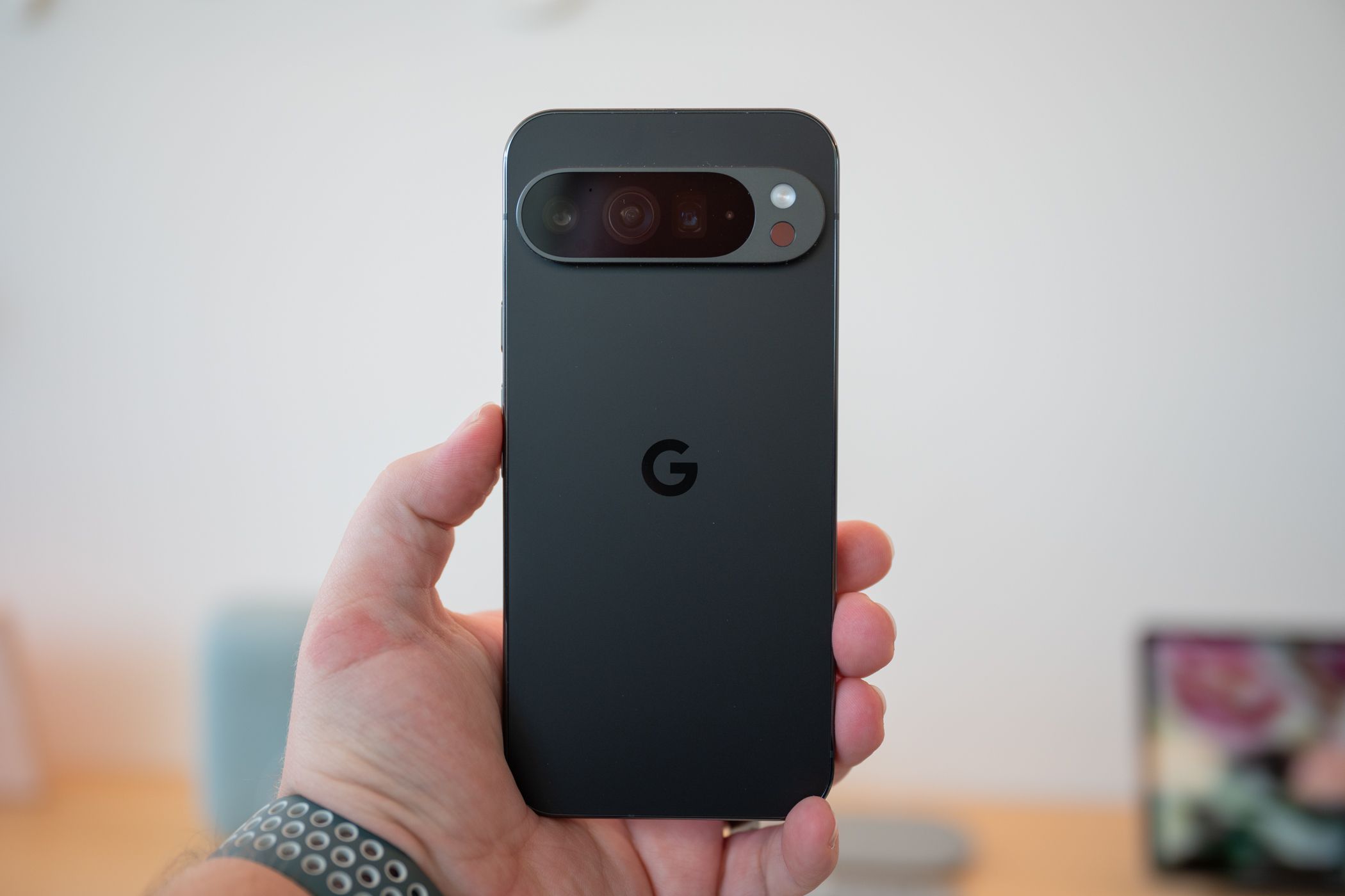 Hand holding Google Pixel 9 series in black.