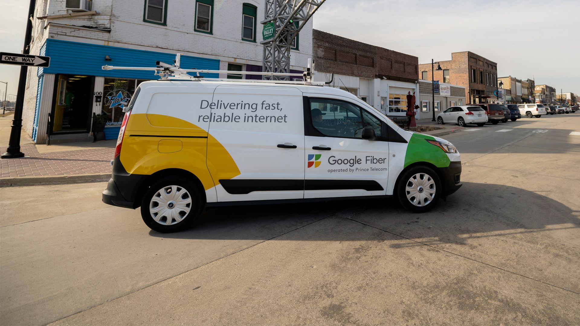 A Google Fiber van parked on a street under an arch.