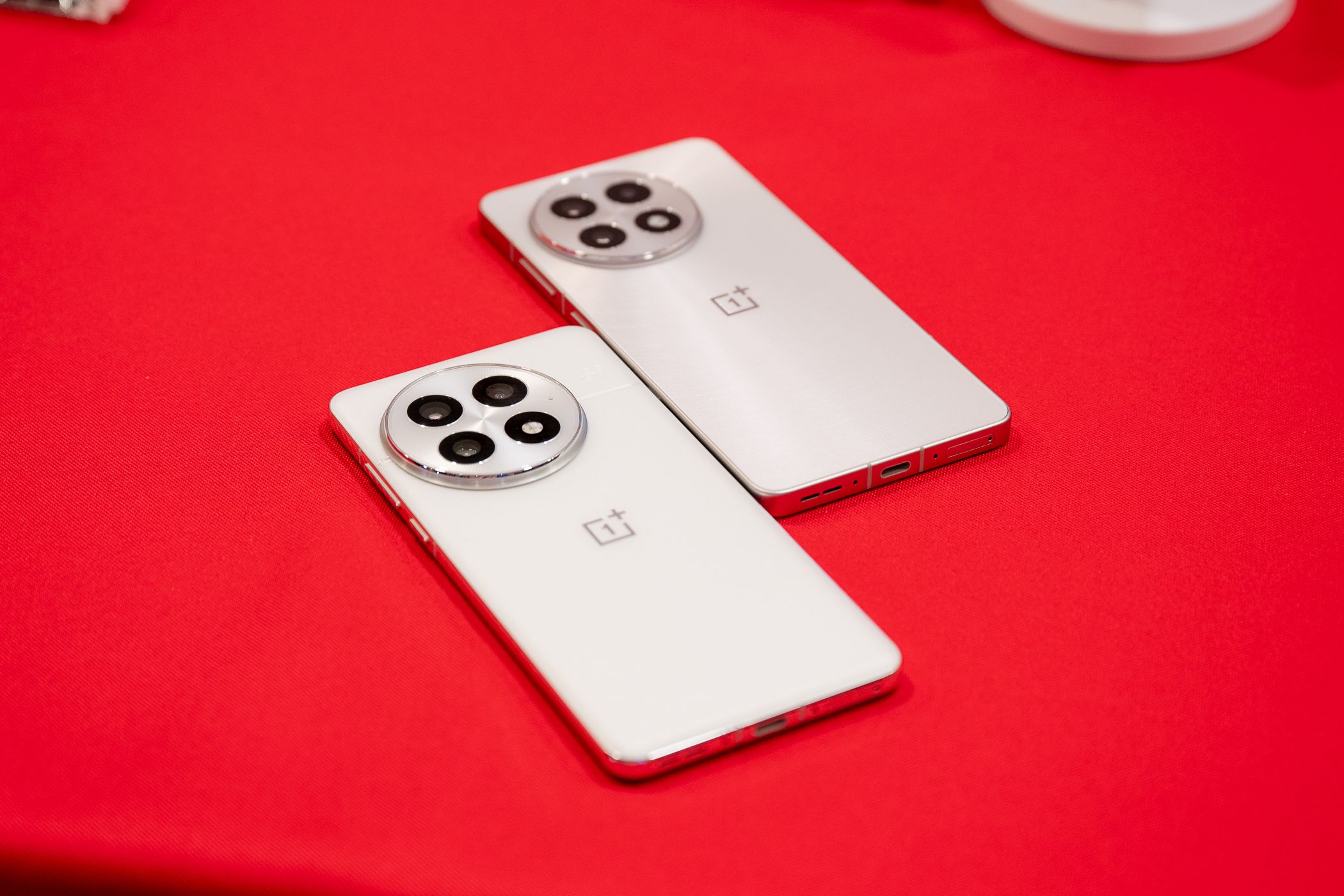 OnePlus 13 and 13R in white laying on a table.
