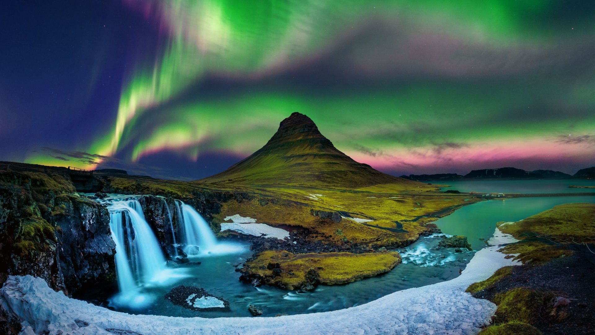 Aurora visible over a mountain and waterfalls. 