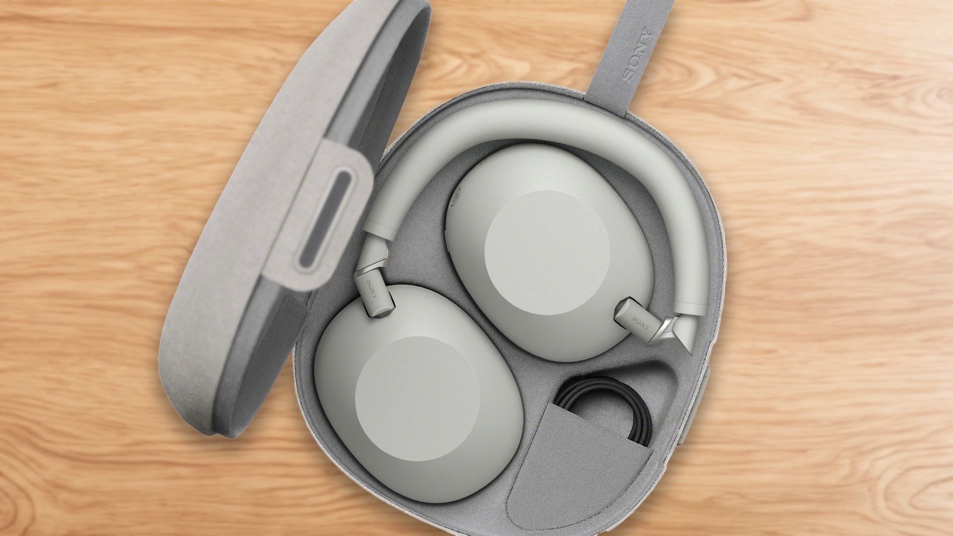 Sony WH-1000XM6 headphones in a carrying case on a wooden surface.