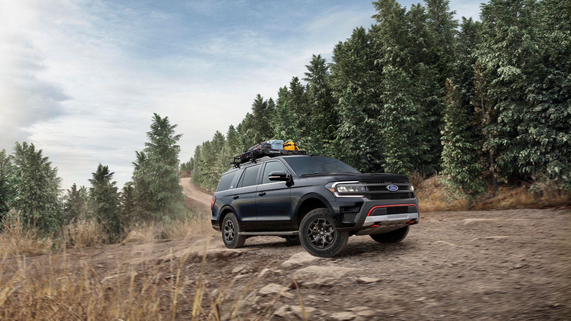 Dynamic front 3/4 shot of a 2024 Ford Expedition Timberline off-roading with trees in the background.