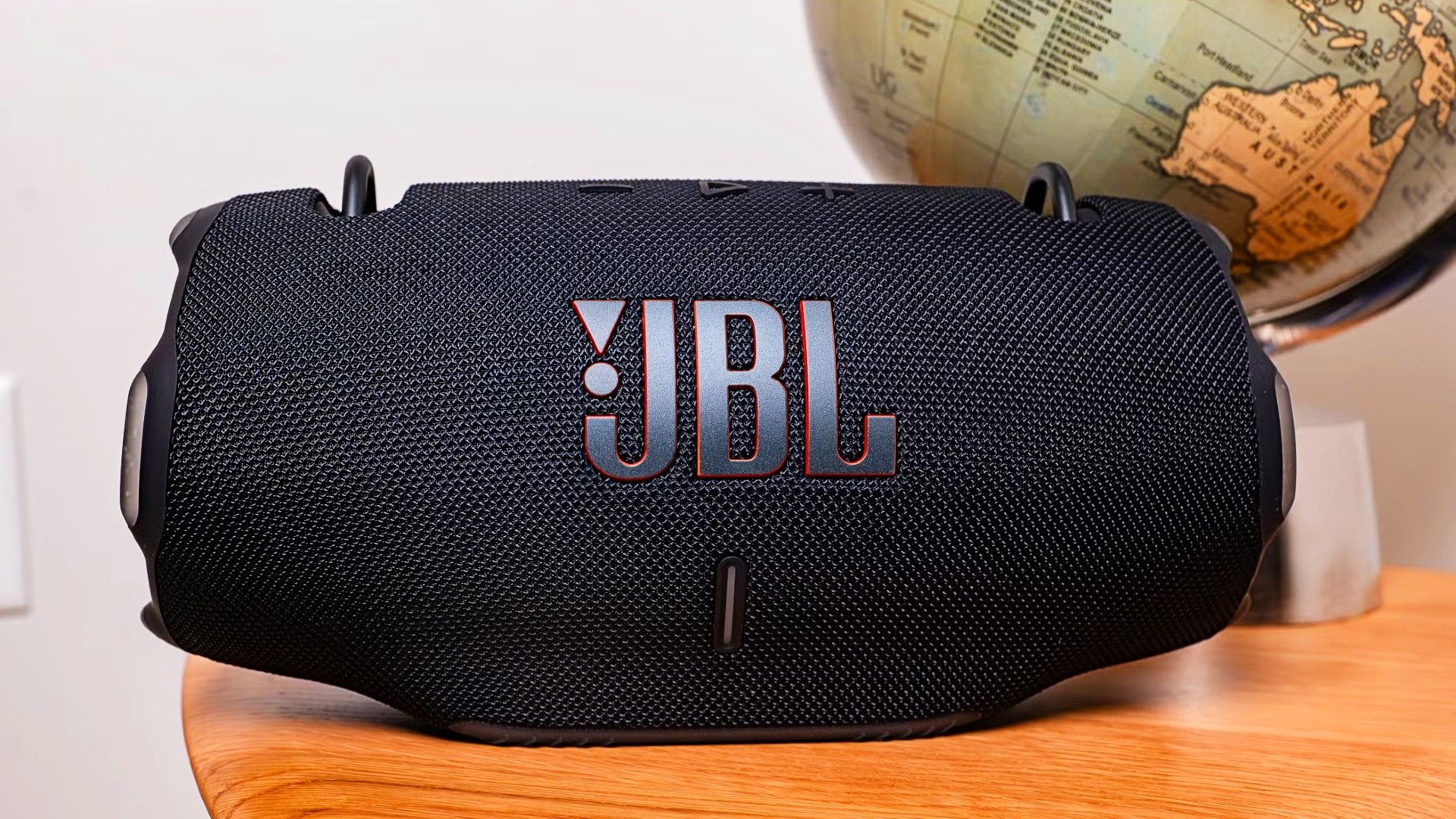 A JBL Extreme 4 on a table near a globe.