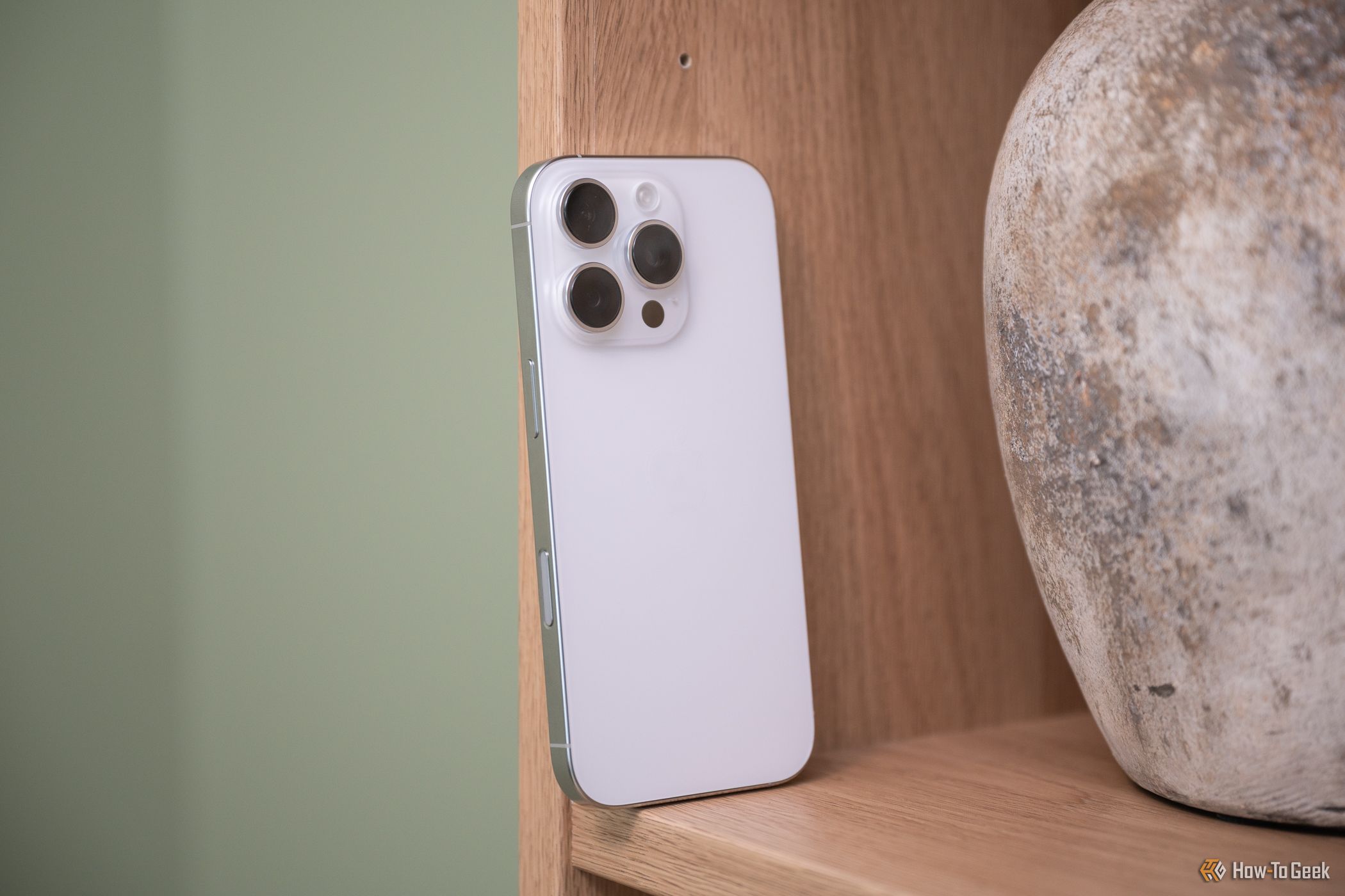 Apple iPhone 16 Pro sitting on a bookcase showing the Camera Control button-2-1