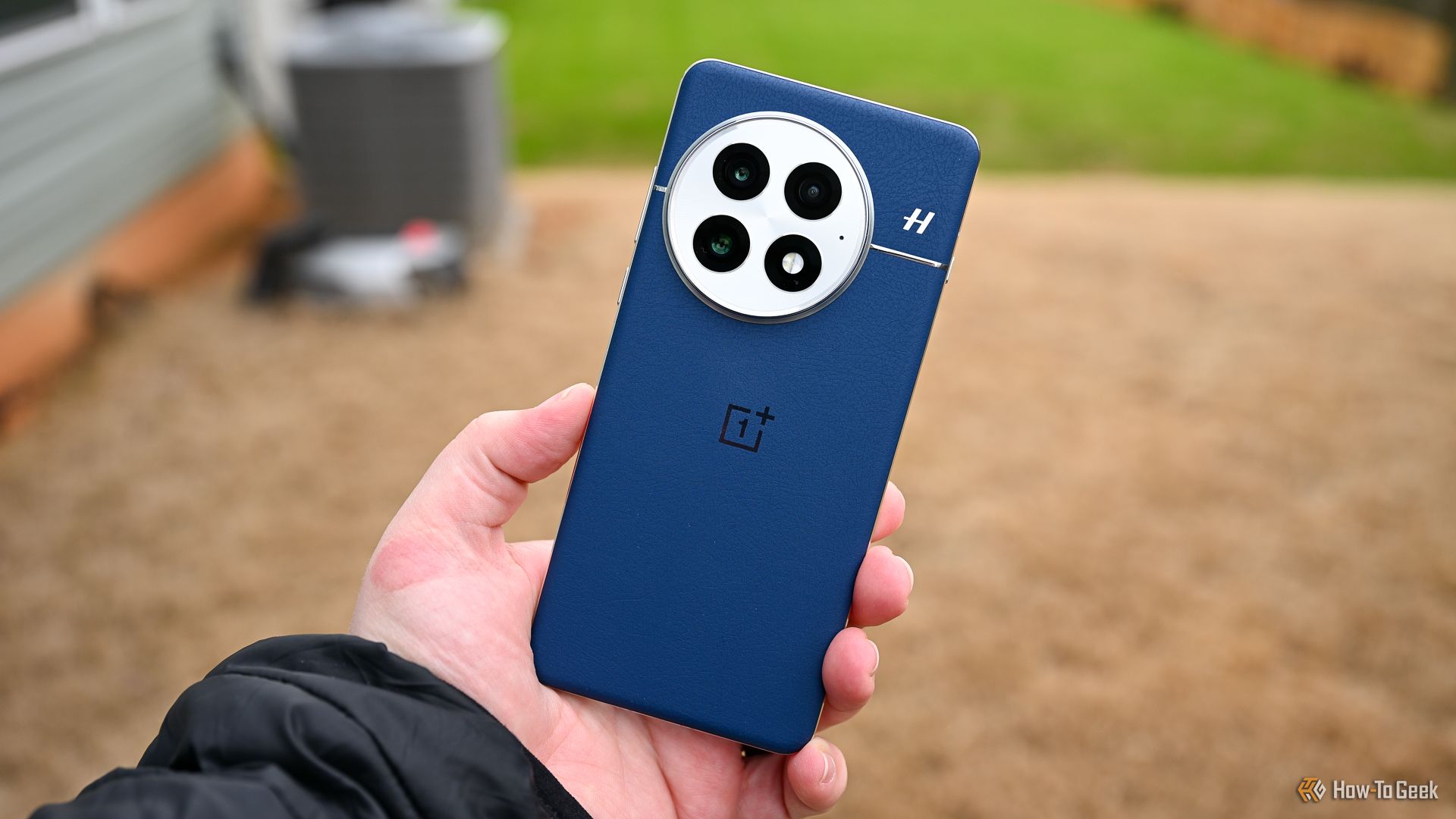 Person holding the OnePlus 13 in blue showing the back of the phone and camera.
