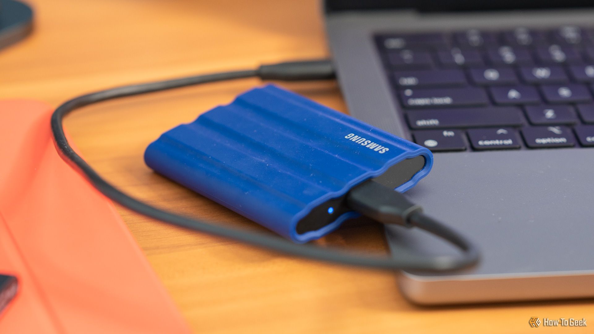 Samsung T7 Shield SSD sitting next to an Apple MacBook computer.