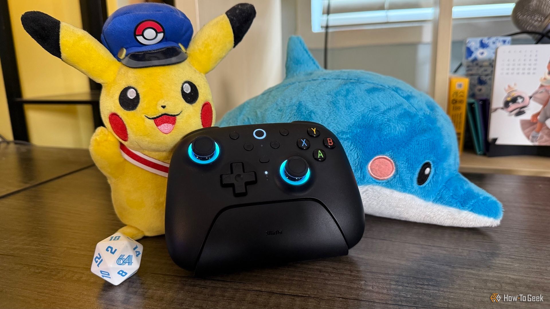 8BitDo Ultimate 2 Wireless Controller on a table surrounded by gaming items.
