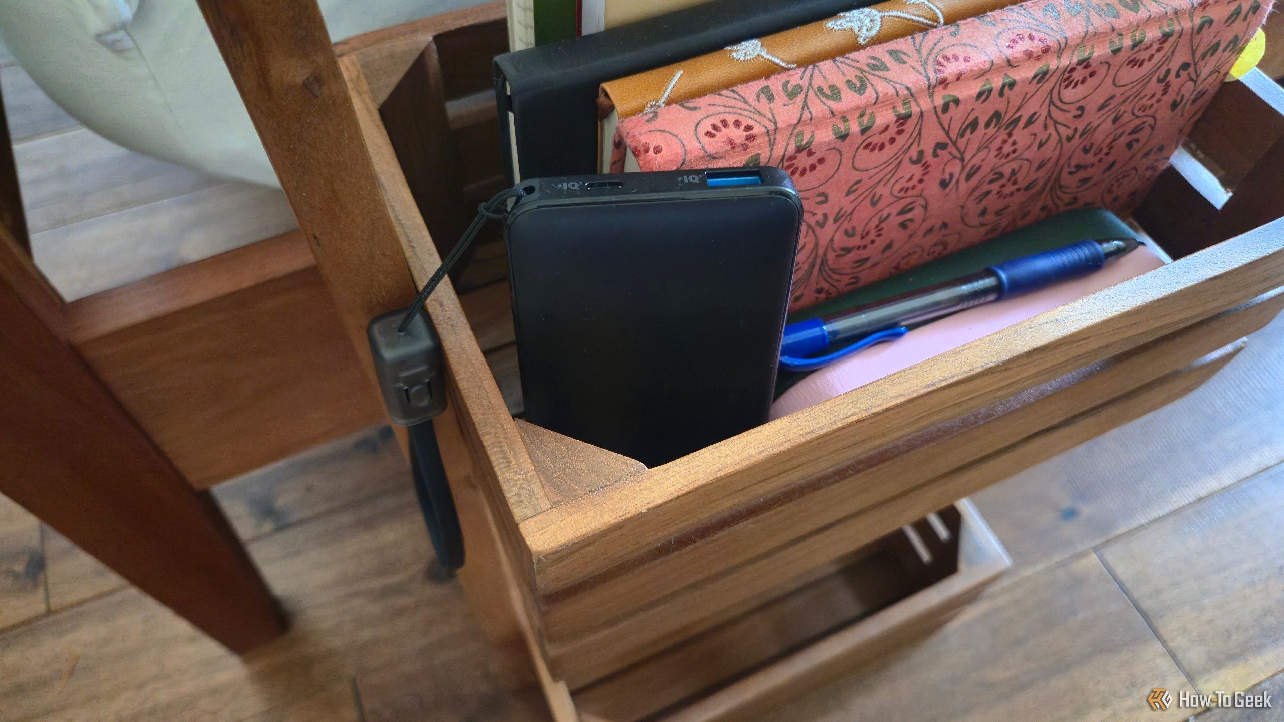 An Anker portable power bank in a basket next to a bed.