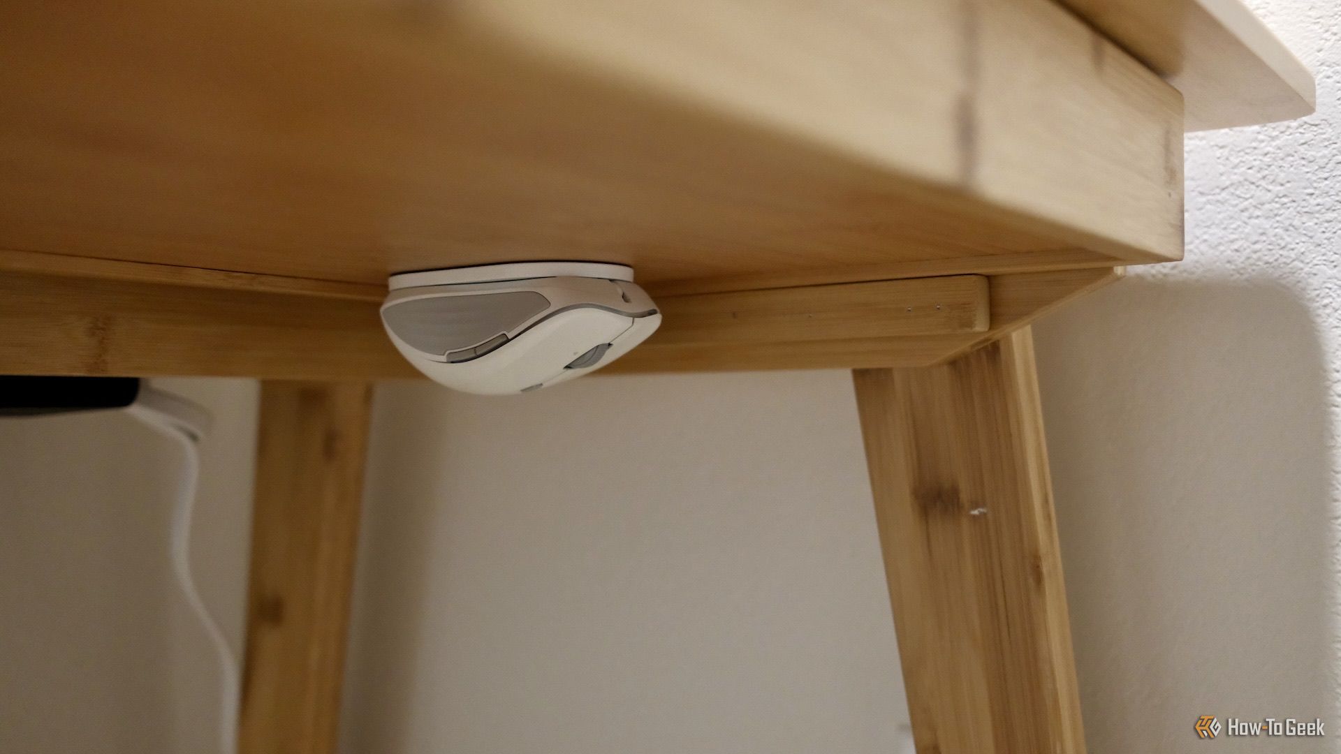 The ESR MagMouse upside down stuck to a magnet pad under a desk.